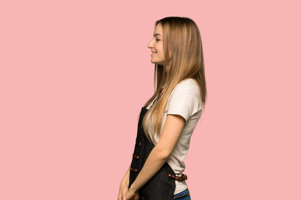 Giovane donna con grembiule in posizione laterale su fondo rosa isolato
 - Foto, immagini