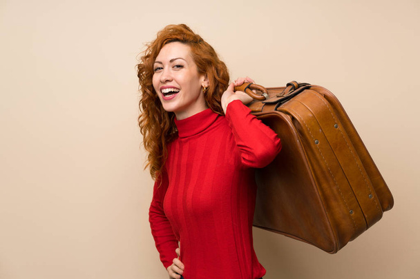 Рыжая женщина в свитере с водолазкой держит винтажный портфель
 - Фото, изображение