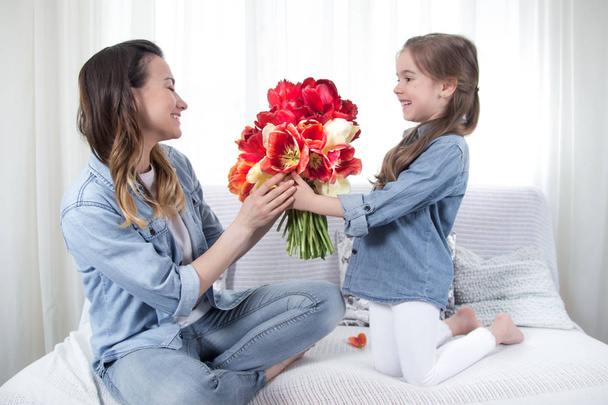 Muttertag. Kleine Tochter mit Blumen gratuliert ihrer Mutter - Foto, Bild