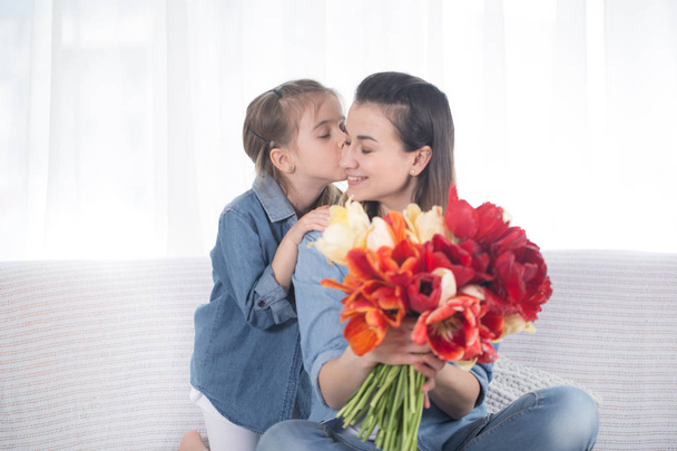 Dzień matki. Mała córka z kwiatami gratuluje swojej matce - Zdjęcie, obraz