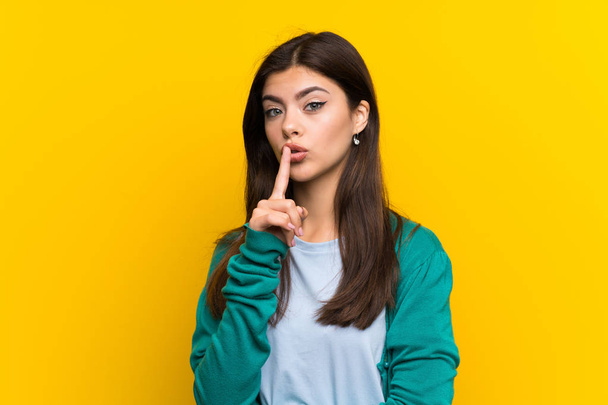 Tinédzser lány csinál csend gesztus sárga falon - Fotó, kép