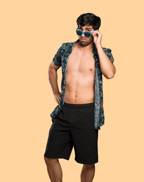 Man in trunks with glasses and surprised over isolated yellow background - Foto, immagini