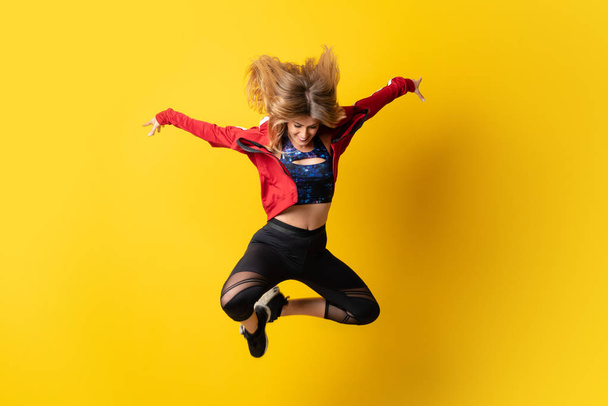 Bailarina urbana dançando sobre fundo amarelo isolado e pulando
 - Foto, Imagem