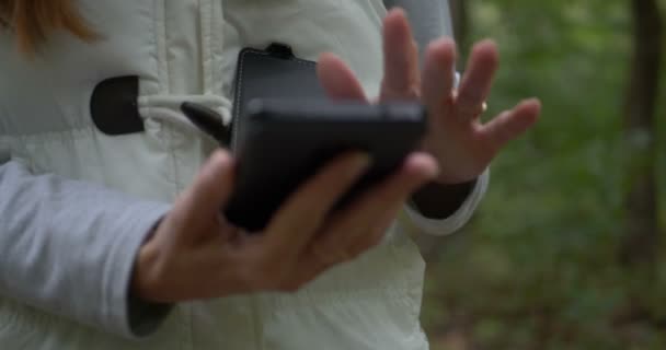 fiatal nő megnyitja okostelefonját, hogy keressen információt az erdőben tavasszal slo-mo - Felvétel, videó