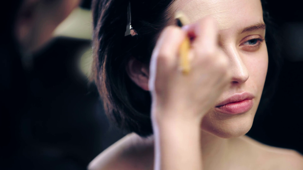 make-up umělec aplikování základů na modelový obličej s kosmetickým kartáčkem - Záběry, video