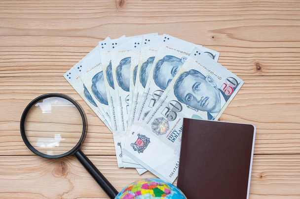 Τραπεζογραμμάτιο χρημάτων με διαβατήριο, μεγεθυντικό φακό, σφαίρα σε ξύλινο  - Φωτογραφία, εικόνα