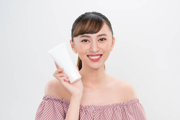 jovem sorridente mostrando produtos de cuidados com a pele
  - Foto, Imagem