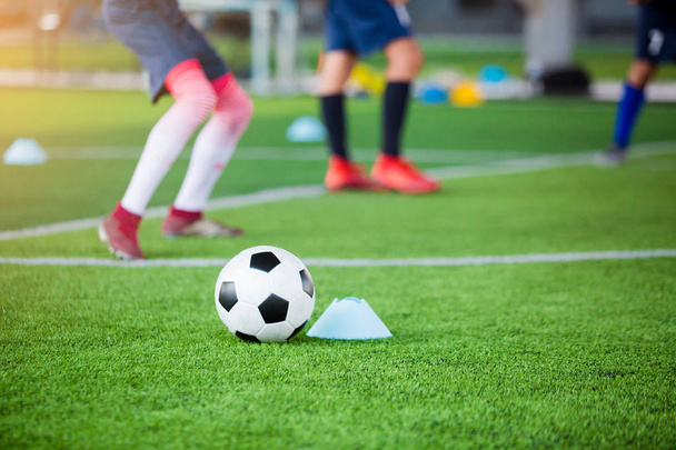 Ποδόσφαιρο μεταξύ κώνους δείκτη σε πράσινο τεχνητό χλοοτάπητα με θόλωμα - Φωτογραφία, εικόνα