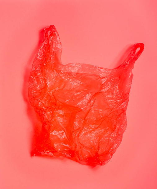 Bright red plastic bag on light red background. - Fotografie, Obrázek