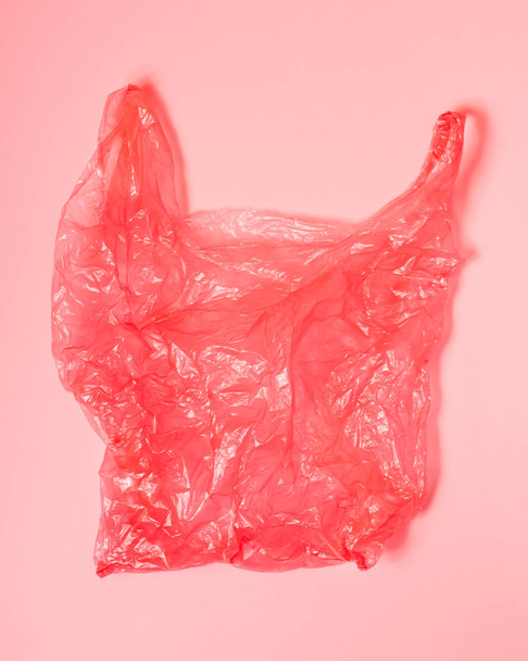 Bright red plastic bag on light red background. - Foto, Imagen
