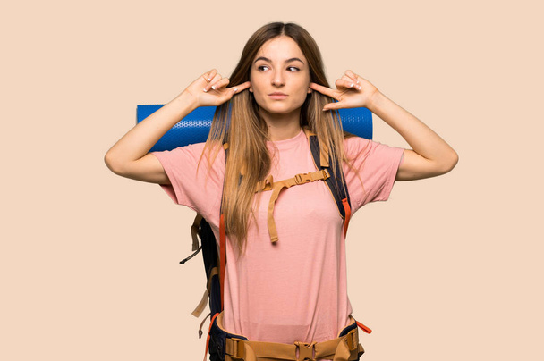 Nuori backpacker nainen kattaa molemmat korvat kädet eristetty keltainen tausta
 - Valokuva, kuva