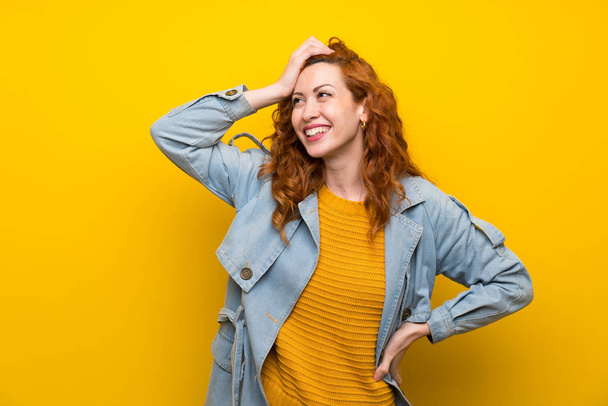 Redhead woman over isolated yellow background laughing - Foto, afbeelding