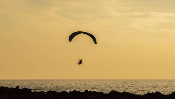 Desporto aéreo extremo ao pôr-do-sol no mar
 - Foto, Imagem