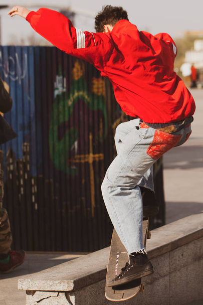 Young guys in stylish clothes ride a skateboard in the park. - 写真・画像
