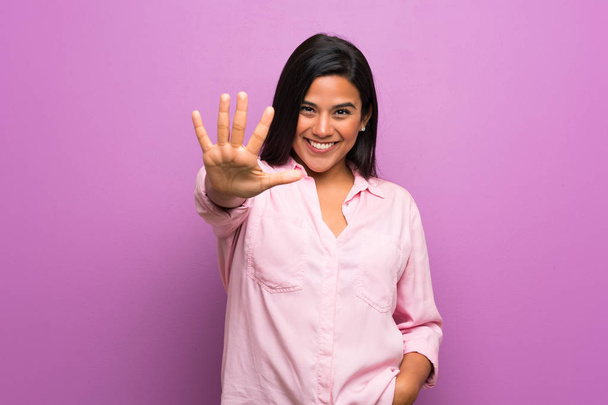 Młoda Kolumbijka nad fioletową ścianą liczy pięć palców - Zdjęcie, obraz