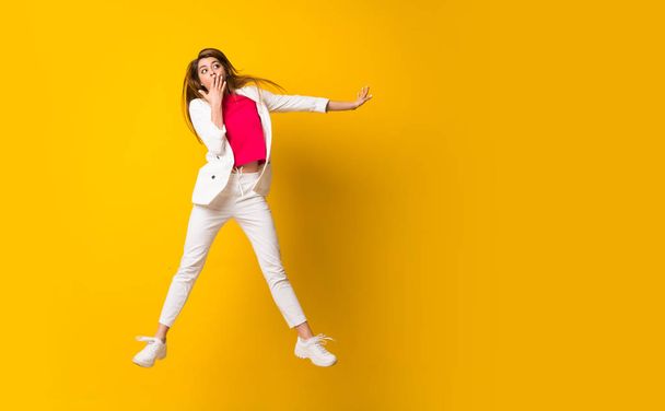Young woman jumping over isolated yellow wall - Foto, Bild