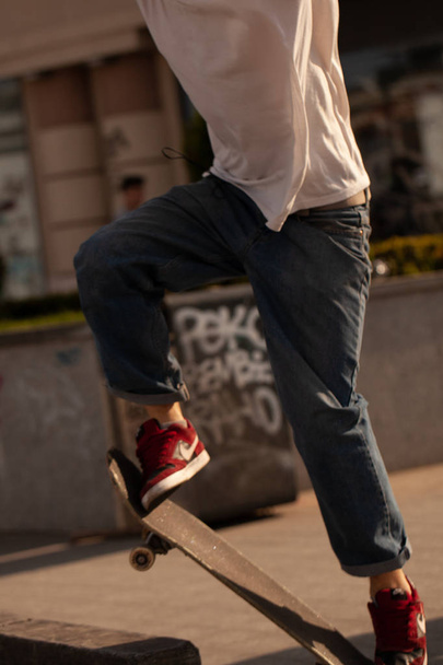 Young guys in stylish clothes ride a skateboard in the park. - Foto, imagen