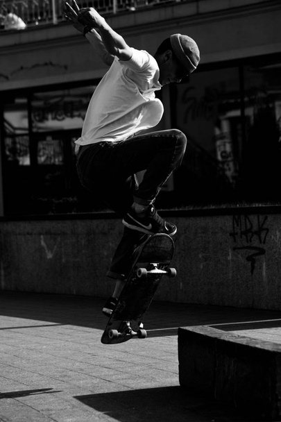 Young guys in stylish clothes ride a skateboard in the park. - Foto, afbeelding