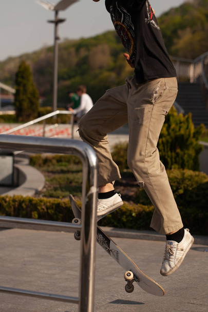 Giovani in abiti eleganti cavalcano uno skateboard nel parco
. - Foto, immagini