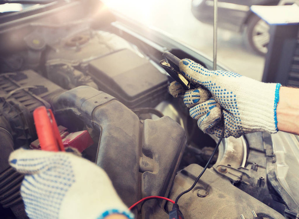 auto mechanic man with cleats charging battery - Фото, изображение