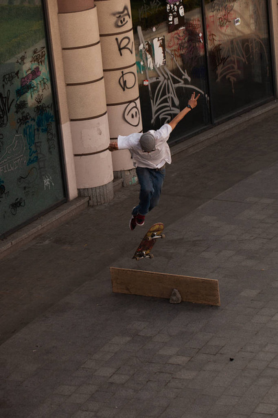 Jonge jongens in stijlvolle kleren rijden op een skateboard in het park. - Foto, afbeelding