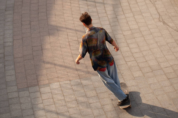 Young guys in stylish clothes ride a skateboard in the park. - Foto, imagen