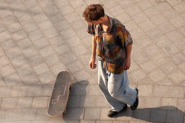 Young guys in stylish clothes ride a skateboard in the park. - Photo, Image
