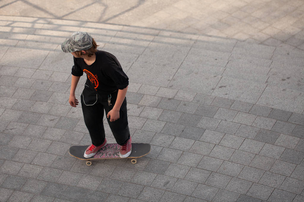 Jonge jongens in stijlvolle kleren rijden op een skateboard in het park. - Foto, afbeelding