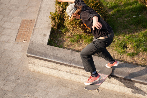 Young guys in stylish clothes ride a skateboard in the park. - Photo, Image