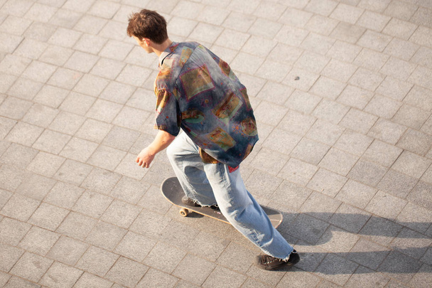 Young guys in stylish clothes ride a skateboard in the park. - Foto, Imagem