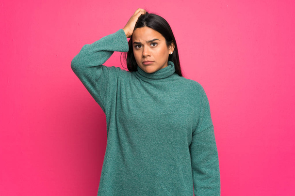 Young Colombian girl with green sweater with an expression of frustration and not understanding - Photo, Image