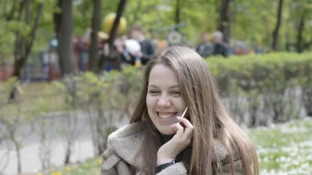 Woman smiling and talking on mobile phone in city park - Filmmaterial, Video
