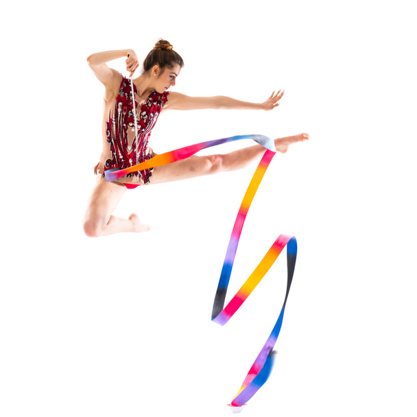 Девушка занимается художественной гимнастикой с прыжками с ленты
 - Фото, изображение