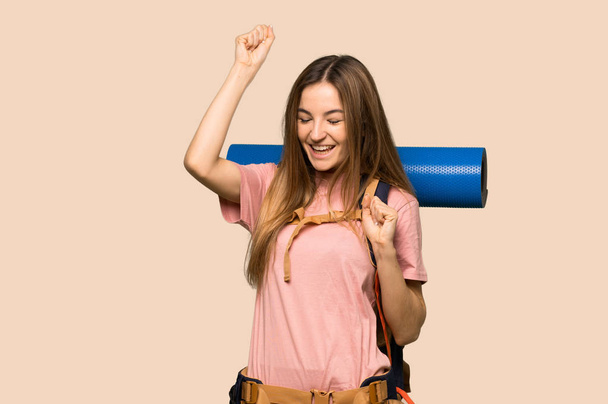 junge Backpacker-Frau feiert einen Sieg auf isoliertem gelben Hintergrund - Foto, Bild