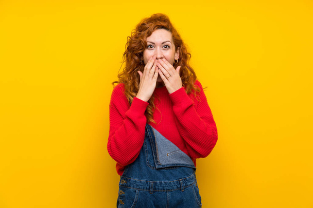 Červenovlasá žena s oděvy přes izolovanou žlutou zeď s překvapením na tváři - Fotografie, Obrázek