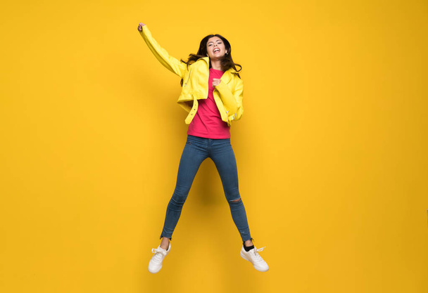 Tiener meisje springen over geïsoleerde gele muur - Foto, afbeelding
