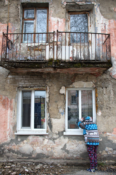 Barnaul,Russia-may 1, 2019. A woman stands near the Windows of an old house - Photo, Image
