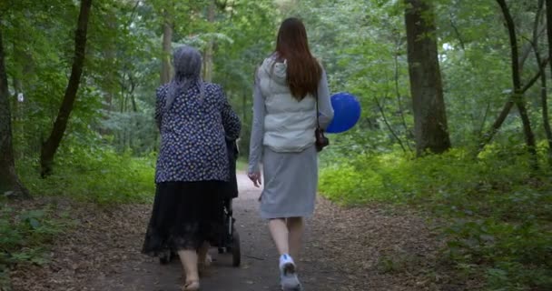Young and old woman strolling in a orest with a pram in a forest in slo-mo - Footage, Video