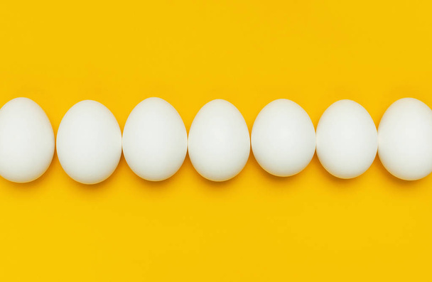 Kreative Lebensmittel minimalistischen Hintergrund, Ostern. weiße Hühnereier auf gelbem Hintergrund von oben flach legen Kopierraum. Natürliche gesunde Ernährung und ökologischer Landbau. - Foto, Bild