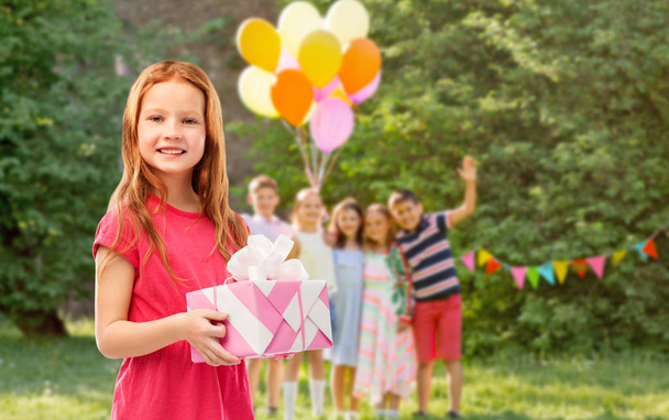 rood haired meisje met geschenk op verjaardagsfeestje - Foto, afbeelding