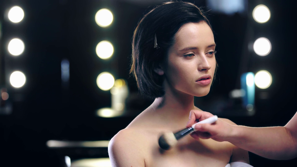 vista parcial de maquillaje artista en polvo modelo cuello con cepillo cosmético
 - Imágenes, Vídeo