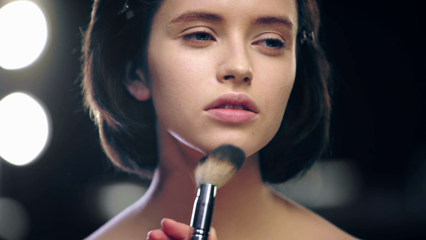 vista recortada de maquillaje artista en polvo modelo de piel con cepillo cosmético
 - Metraje, vídeo