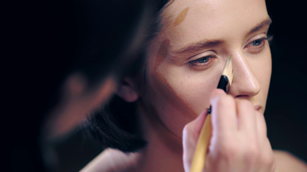 makijaż artysta robi konturowanie na twarz modelu z ciemnej twarzy Fundacji i kosmetycznych pędzla - Materiał filmowy, wideo