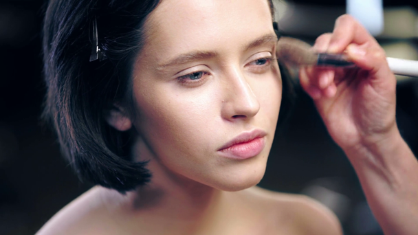 maquillador aplicando polvo facial en la cara modelo con cepillo cosmético
 - Imágenes, Vídeo