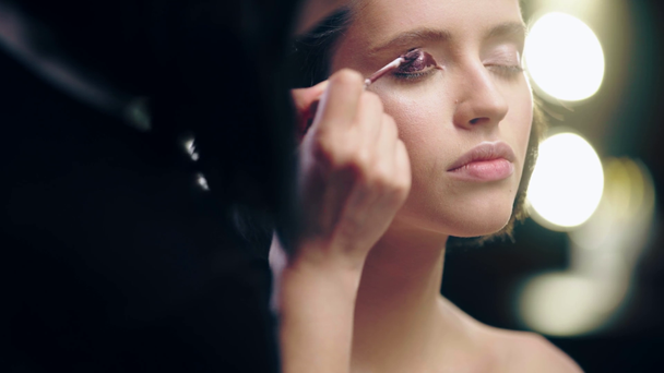 cropped view of makeup artist applying liquid brown eye shadow on model eyelid - Filmmaterial, Video