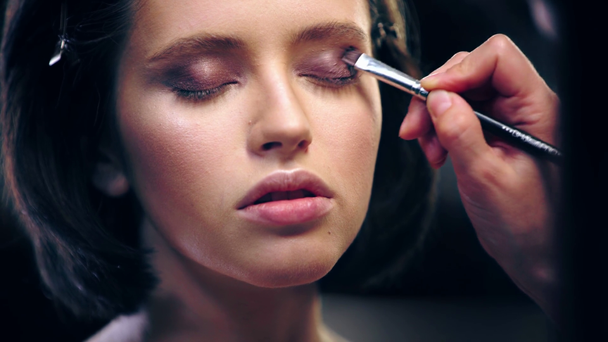 vista parcial del artista de maquillaje sombreado sombra de ojos marrón líquido en el párpado modelo
 - Metraje, vídeo