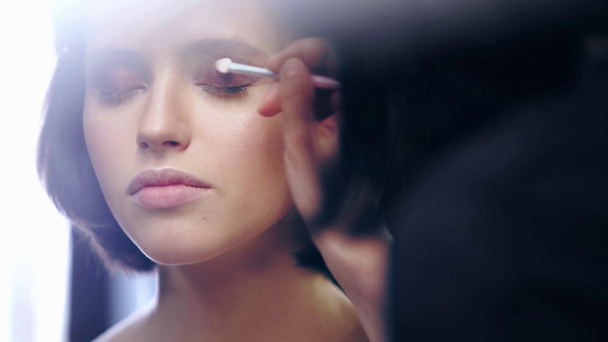 enfoque selectivo del artista de maquillaje sombreado sombra de ojos marrón líquido en el párpado modelo con cepillo cosmético
 - Imágenes, Vídeo
