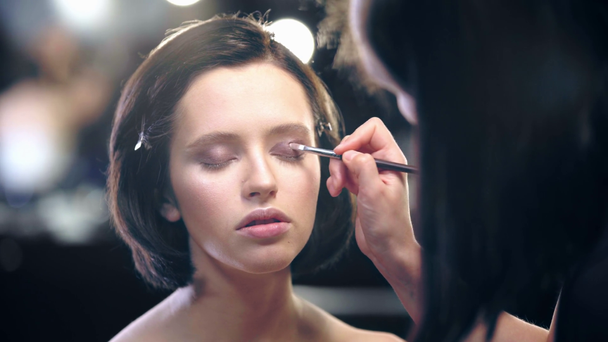 selektywne ostrości makijażu artysty stosując ciecz brązowy cień do powiek na powiece modelu z pędzlem kosmetycznym - Materiał filmowy, wideo