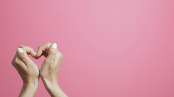 Frauen herzförmige Hände, kreative Liebeserklärung, Live-Postkarte, Herzschläge auf rosa Studiohintergrund - Filmmaterial, Video