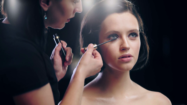 化粧品ブラシでモデルのまつげにマスカラを塗るメイクアップアーティストのトリミングビュー - 映像、動画